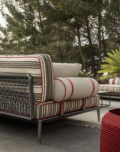 a set of outdoor furniture sitting on top of a cement floor next to trees and bushes