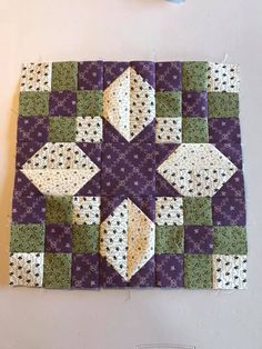 a purple and green patchwork quilt is laying on the floor next to a pair of scissors