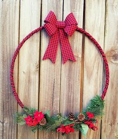 a red and black christmas wreath with pine cones, poinsettis and bows