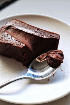 a piece of chocolate cake on a white plate with a spoon