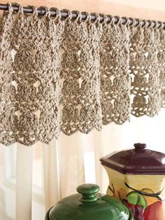 a kitchen curtain with crocheted lace hanging from it's valance over a window