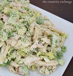 a white plate topped with pasta and lettuce covered in cheese dressing next to a fork