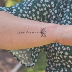 a woman with a small tattoo on her arm that reads, resiline in cursive writing