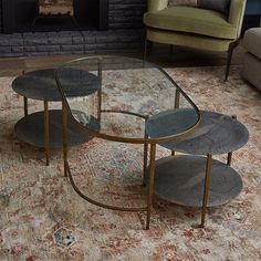 three glass tables sitting on top of a rug in front of a fire place and couch