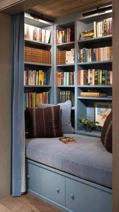 a window seat in the corner of a room with bookshelves and shelves full of books