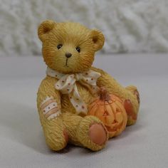 a brown teddy bear sitting next to a pumpkin