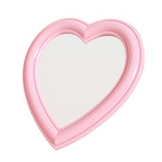 a pink heart shaped mirror sitting on top of a table