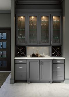 a kitchen with gray cabinets and white counter tops, along with wine glasses on the glass doors