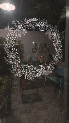 the reflection of a table and chairs in a glass window with a wreath drawn on it