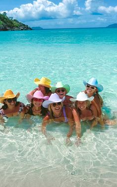 a group of girls in the water wearing sunhats and hats on their heads