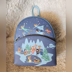 Loungefly Disney Peter Pan Starnite Backpack. This Bag Features A Scene Of Peter Pan And The Darling Children Flying Over Neverland With The Lost Boys, Tick Tock, And Captain Hook Below. This Bag Has Adjustable Straps, An Outer Zipped Pocket, And An Interior Pocket. New With Tags 9" X 5" X10" Bundle With Other Great Finds In My Closet And Save On Shipping! Blue Disney Backpack With Adjustable Strap, Disney Travel Backpack, Disney Style Backpack For Travel, Disney Themed Standard Backpack For Theme Park, Disney Standard Backpack For Travel, Disney Style Standard Backpack For Travel, Themed Travel Backpack Bags, Blue Backpack For Theme Park, Cute Standard Backpack For Theme Parks