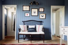 a living room with blue walls and pictures on the wall, including a bench that says happy