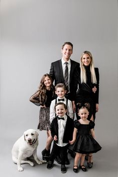 a family posing for a photo with their dog and two children in formal wear, all dressed in black