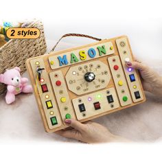 a person holding a wooden toy with the word mason on it and a teddy bear next to it