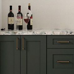 three bottles of wine sitting on top of a counter next to two glasses of wine