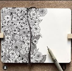 an open notebook with flowers on it and a marker pen next to the book cover