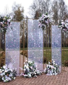 an outdoor ceremony setup with flowers and greenery on the sides, surrounded by glass partitions