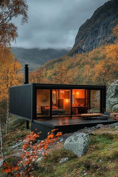 a small cabin in the mountains surrounded by rocks and trees with autumn foliage around it