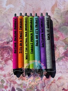 six different colored pens with writing on them in front of a floral wallpapered background