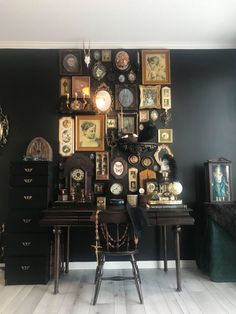 there are many clocks on the wall in this room, and one is sitting at a desk