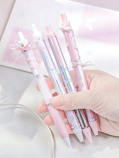 a person holding several pens in their hand with pink and white designs on them,