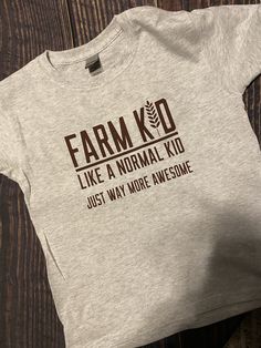 Farm Kid Graphic Tee Farm Graphic Tees, Farm T Shirts, Gray Cotton Shirt With Graphic Print, Pre-shrunk Gray Cotton Shirt, Gray Pre-shrunk Graphic Tee, Fall Short Sleeve T-shirt With Logo Print, Fitted Cotton Slogan Shirt, Fall Logo Print Short Sleeve T-shirt, Gray Graphic Print Tops For All Genders