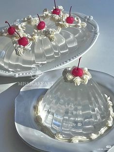 there is a cake with cherries on it and two plates next to each other