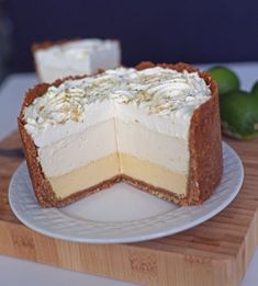 a piece of cake sitting on top of a wooden cutting board next to limes