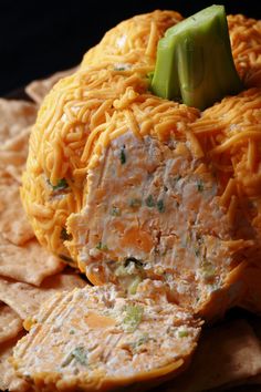 some crackers and cheese are laying on top of the tortilla shell, which is shaped like a pumpkin