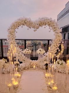 a wedding setup with candles and flowers in the shape of a heart on top of a building