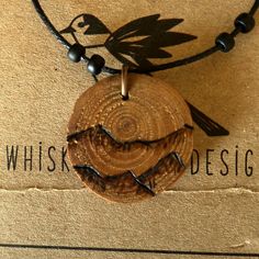 a wooden necklace with black beads and a bird on the disc is sitting on top of a cardboard box