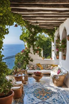 an outdoor patio with potted plants and flowers on the floor, overlooking the ocean