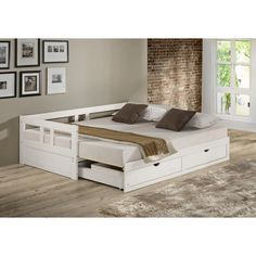 a white bed with drawers underneath it in a living room next to a brick wall