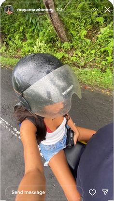 a woman riding on the back of a motorcycle wearing a helmet and holding onto her hand