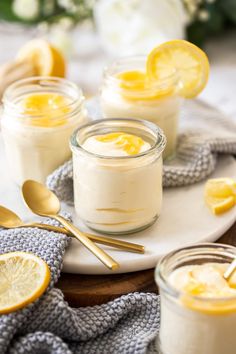 lemon curd mousse in small glass jars on a plate with spoons