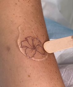 a woman's arm with a tattoo on it that has a flower drawn on it