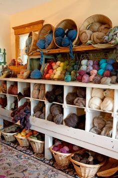 there are many yarns and baskets on the shelves in this room, including balls of yarn