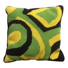 a green, yellow and black pillow on a white background with an abstract design in the middle