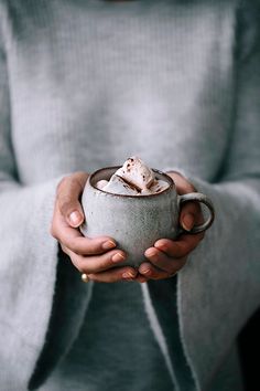 a person holding a cup with some kind of food in it's hands and looking at the camera