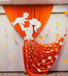 an orange and white backdrop with paper cutouts on the curtain is decorated with daisies