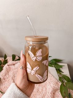 a person holding a jar with a straw in it on top of a pink blanket