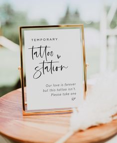 a sign that says temporary tattoo and station on top of a wooden table with feathers