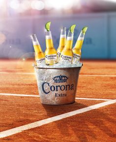 six corona beer bottles in a bucket on a tennis court