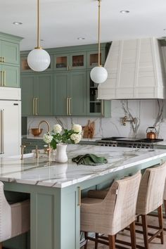 a kitchen with green cabinets and white marble counter tops on the island in front of an oven