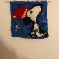 a crocheted wall hanging with a snoopy hat on it's side