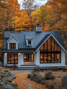 a house in the woods surrounded by fall foliage and trees with leaves on the ground