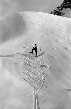 a man riding skis on top of a snow covered slope in the middle of winter