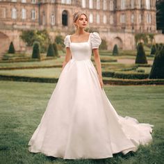 a woman in a white wedding dress standing in front of a large castle like building