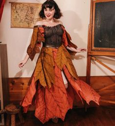 a woman in an orange and brown dress standing on a wooden floor with her arms outstretched