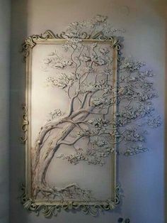 a tree is hanging on the wall in front of a framed photo with an ornate frame